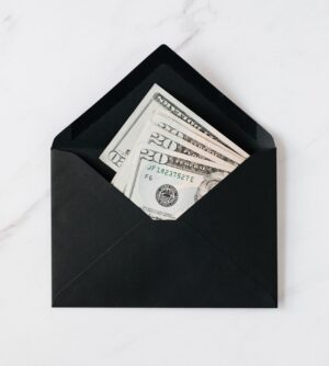 Black envelope on a white and gray background, containing multiple folded 20 dollar bills