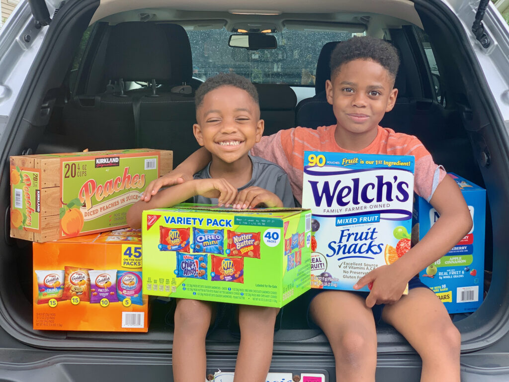 two boys smiling with snacks to help fight summer hunger