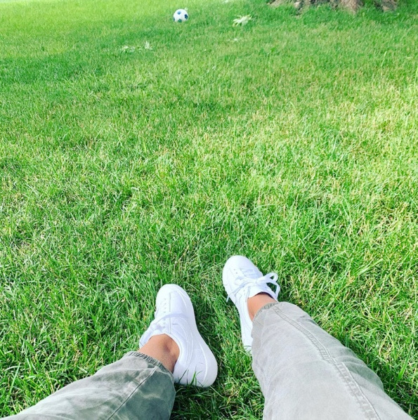 Woman's legs with white sneakers on green grass
