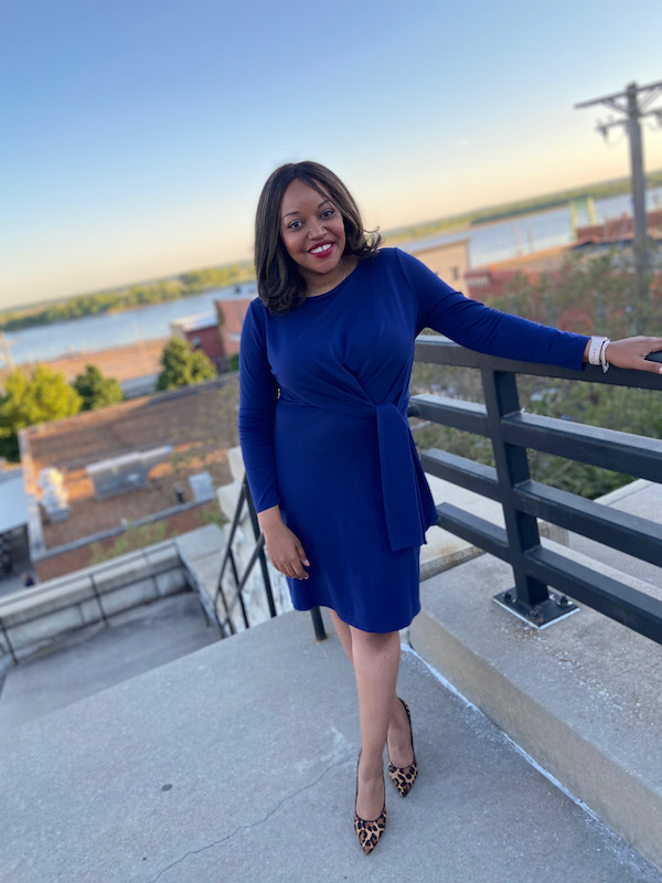 KB in blue dress smiling at camera. Behind her is view of Mississippi River during visit to Alton, Illinois.