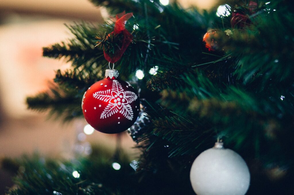 Closeup of a Christmas tree. A red holiday ornament with a snowflake is in focus