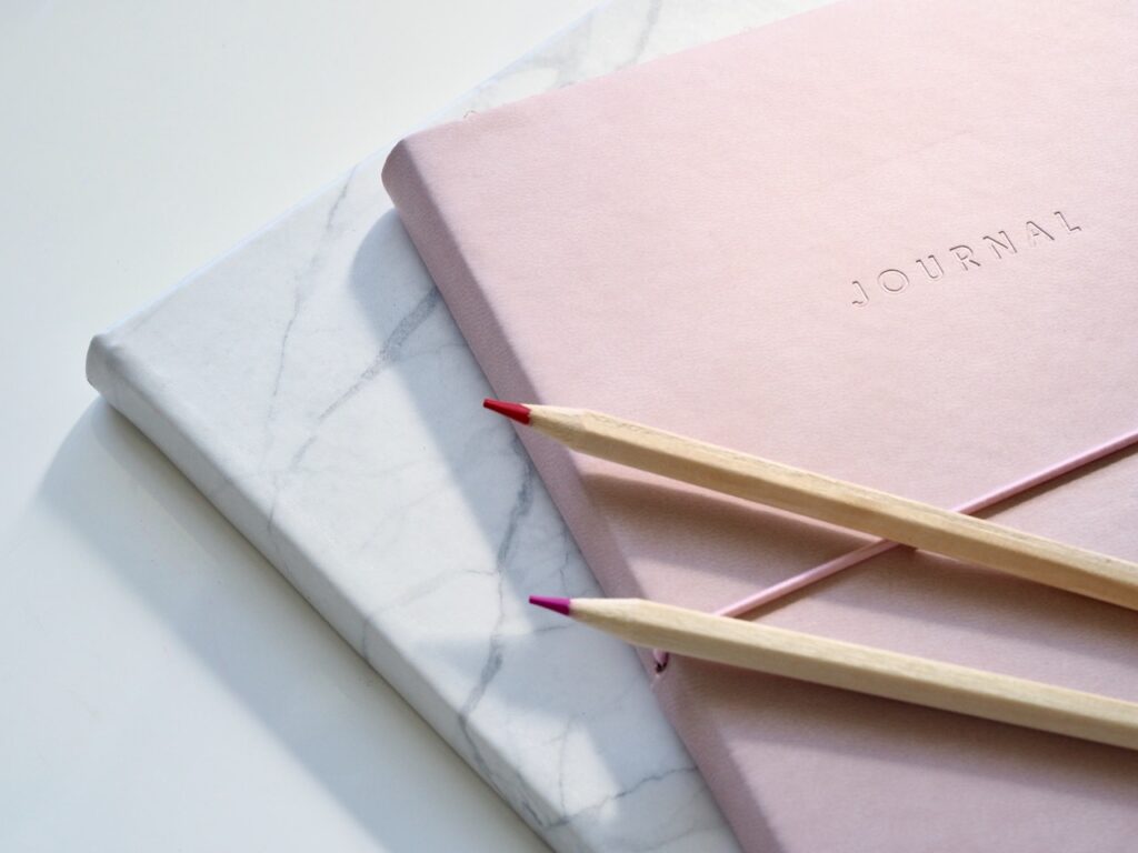 Pink and marble-covered journals for article about gratitude journal writing prompts
