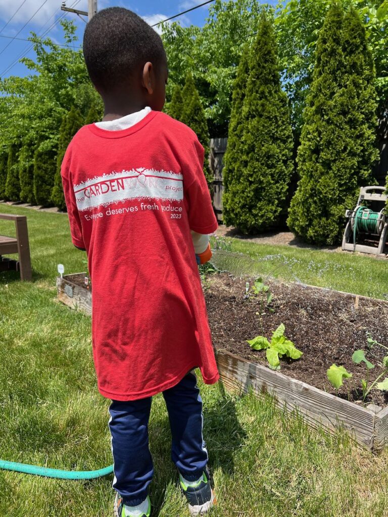 Young boy watering garden during family volunteering with GardenWorks